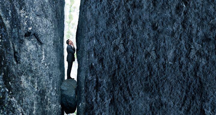 A business man stuck between a rock and hard place