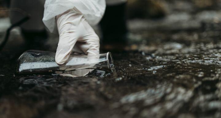 Close up shot of scientist biologist and researcher in protective suit taking water samples