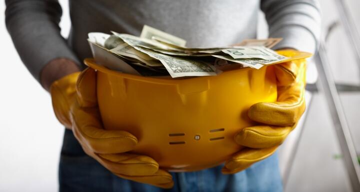 Construction hard hat filled with paper money
