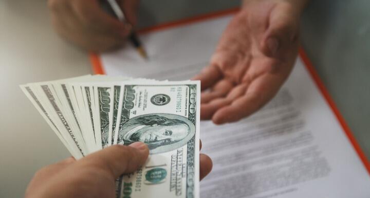 Person paying money in the form of one hundred dollar bills to another person