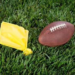 Yellow flag and football on grass