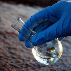 A gloved hand taking a water sample