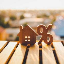 Wooden house and percentage tax icons on wooden table