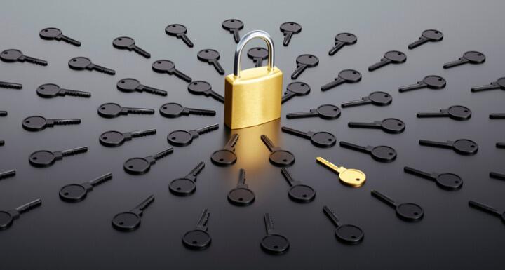 Locked padlock surrounded by a group of black keys with one golden key