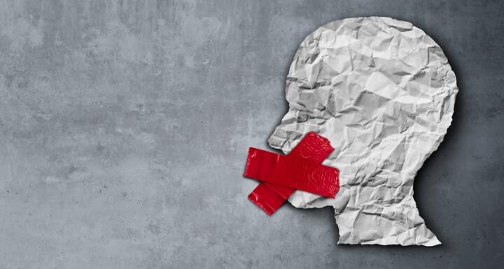 Person paper cut out with red tape over mouth