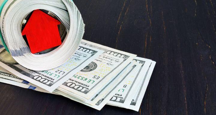 Pile of cash and figure of house.