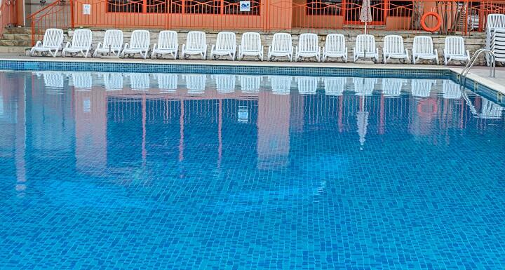Inground pool with white chairs along surround deck