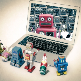 Robot toys surround a laptop with image of robot