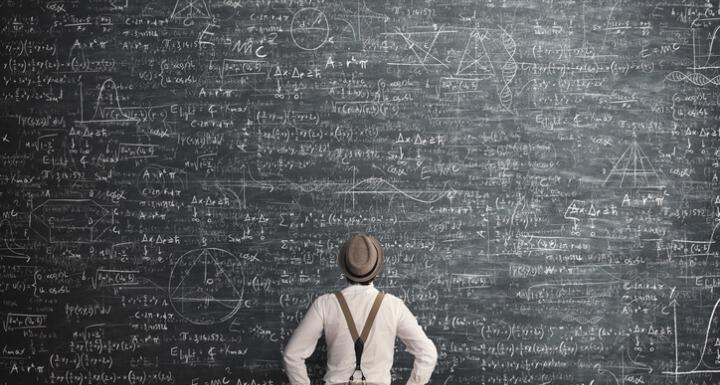 Man facing large chalkboard covered in math equations