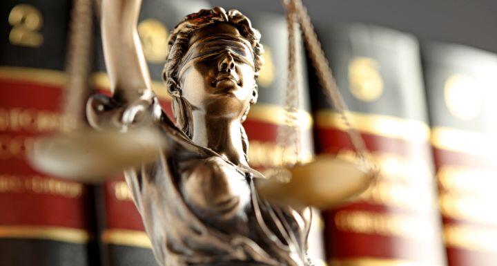Statue Of Lady Justice In Front Of Row Of Law Books