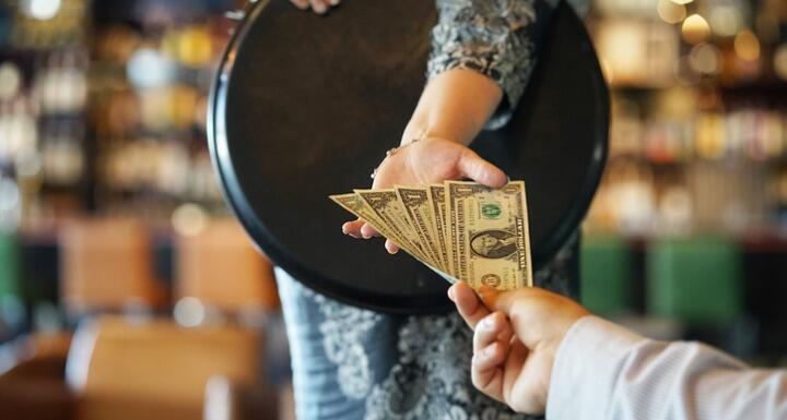 Waitress accepting a tip of multiple dollar bills from a customer