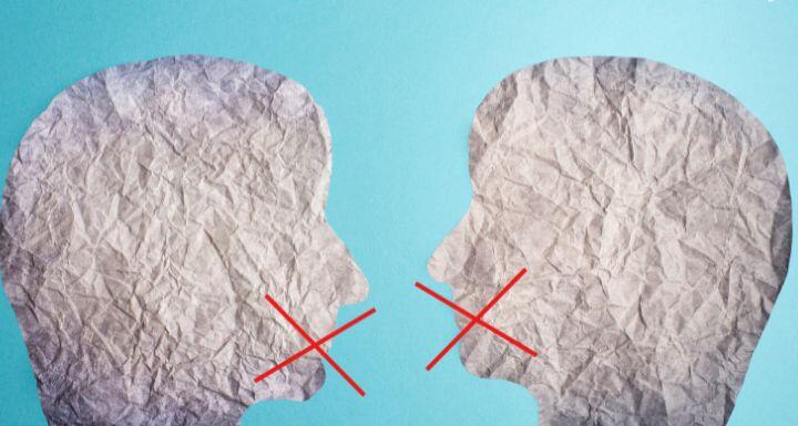 two silhouette faces looak at each other  with red cross over mouth