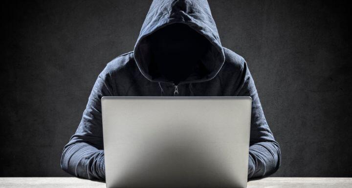 hooded figure using laptop
